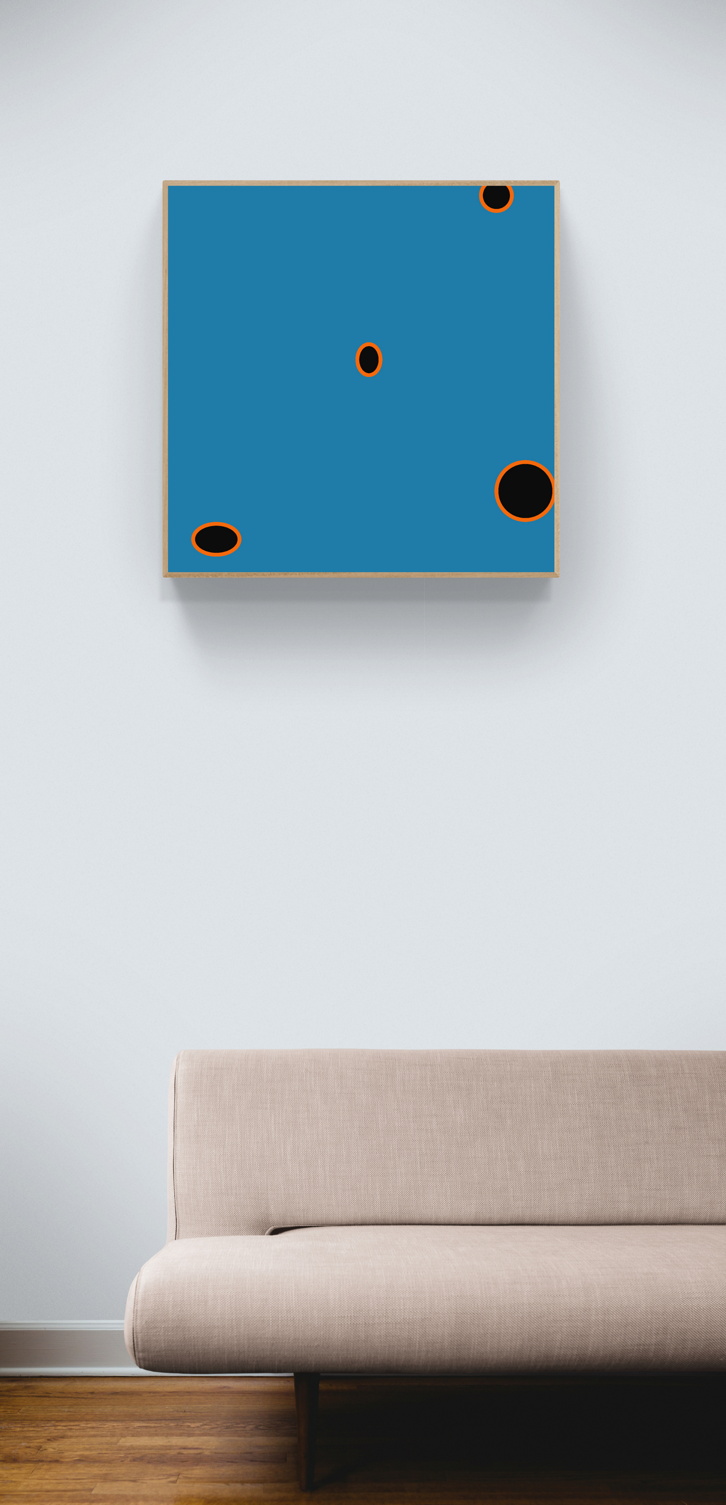 Abstract art print with blue square and black circles on a white wall above a beige sofa.