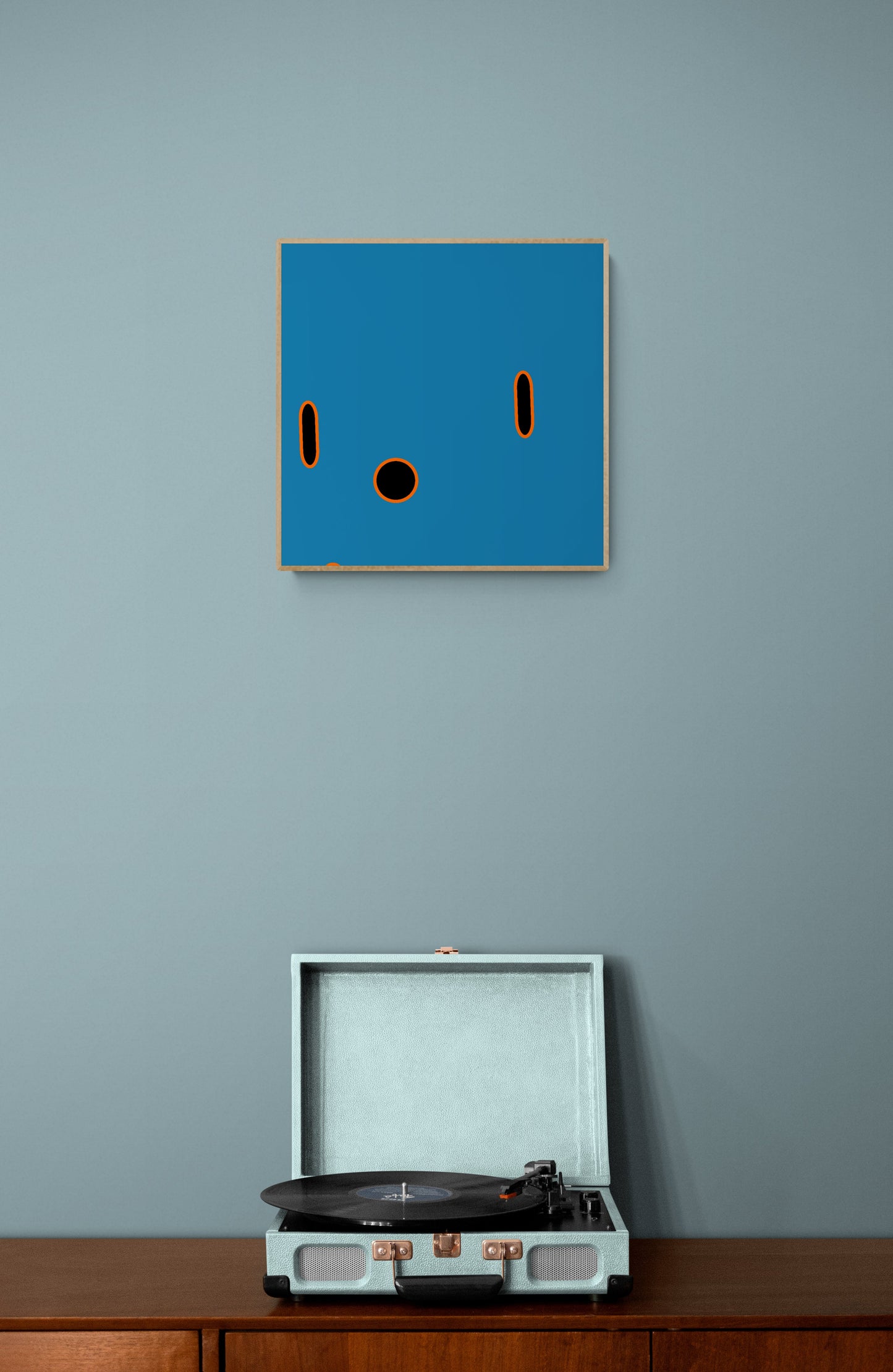 Blue abstract print on a gray wall with a record player below.