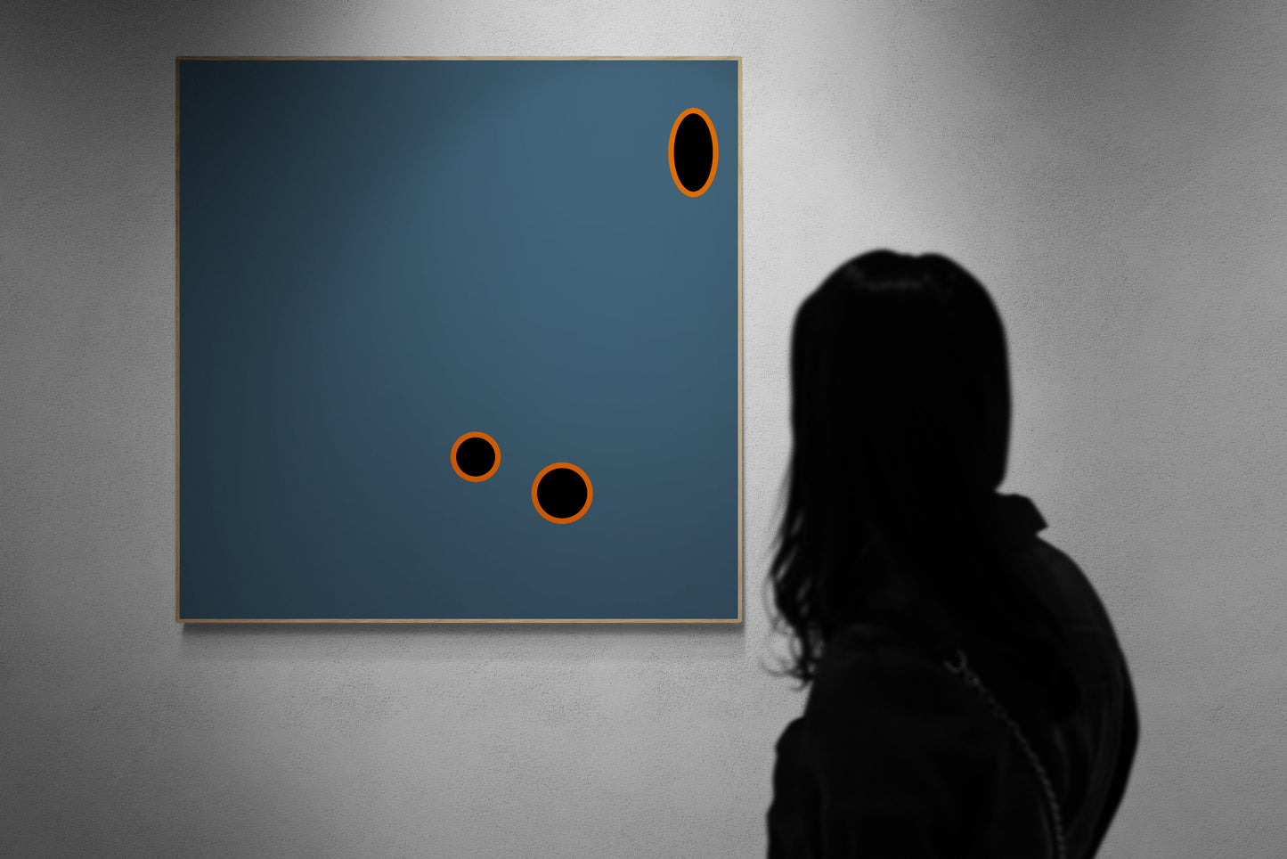 Person viewing an abstract art print with grey background and orange and black circles.