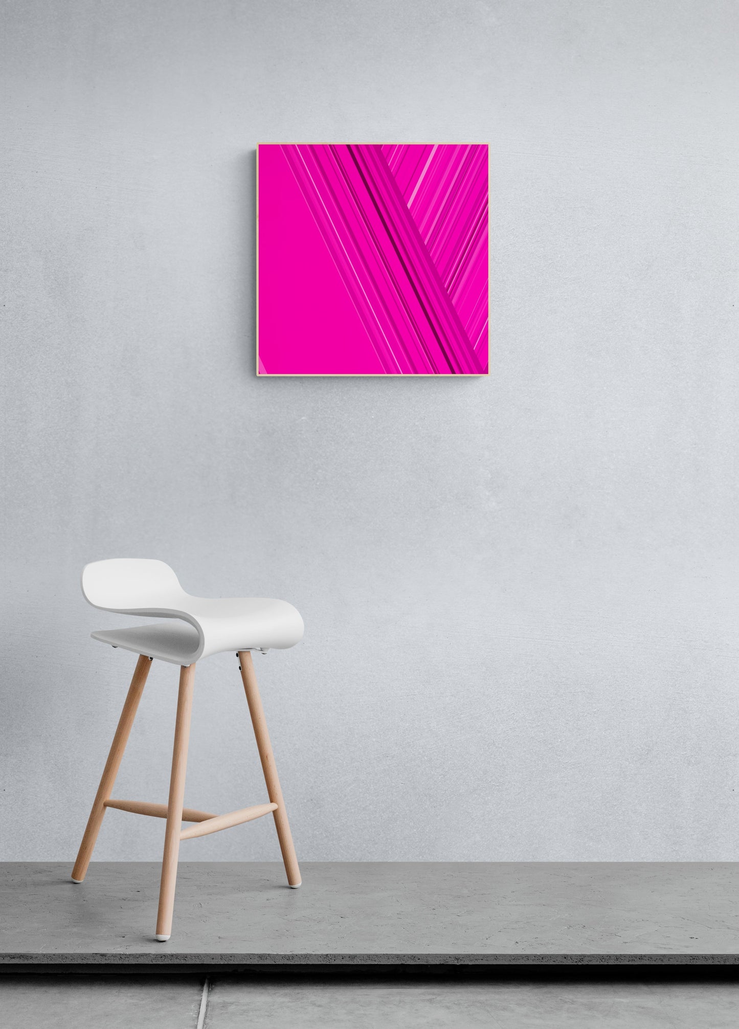 Art print of abstract design with intersecting lines on a pink backgroundon a gray wall with a white stool below.