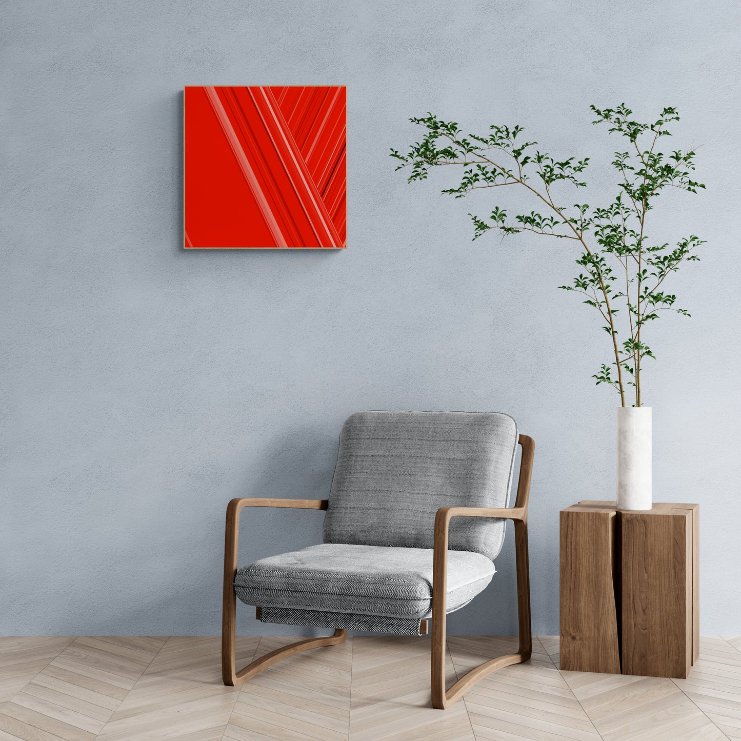 Modern interior with a gray armchair, art print of abstract red design with geometric shapes on a red background, and a plant on a wooden side table.