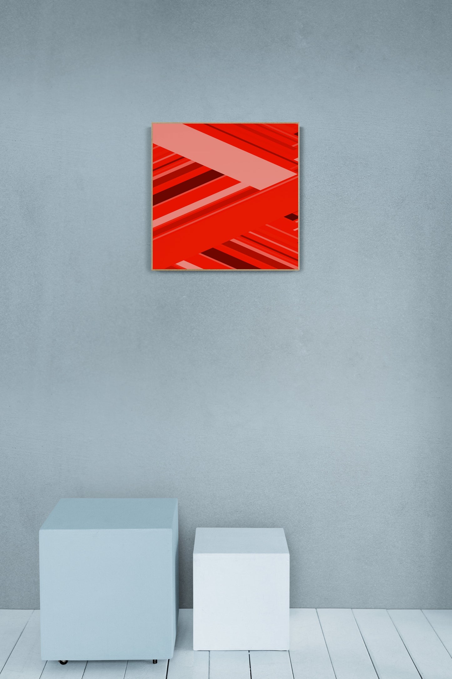 Art print of abstract pattern of red and pink geometric shapes on a gray wall with white cubes on the floor