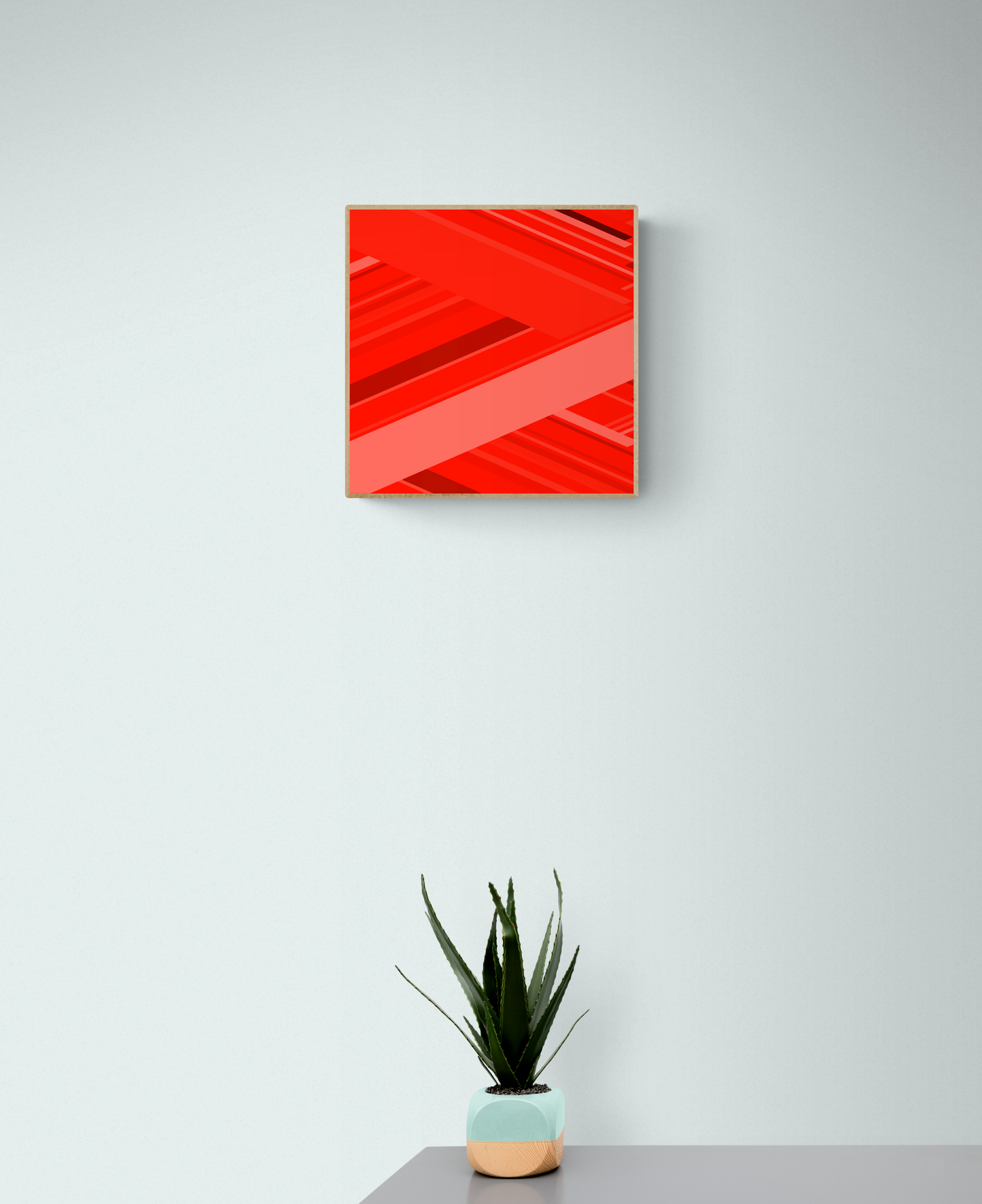 Art print of abstract red design with geometric shapes on a red background on a white wall with a potted plant below