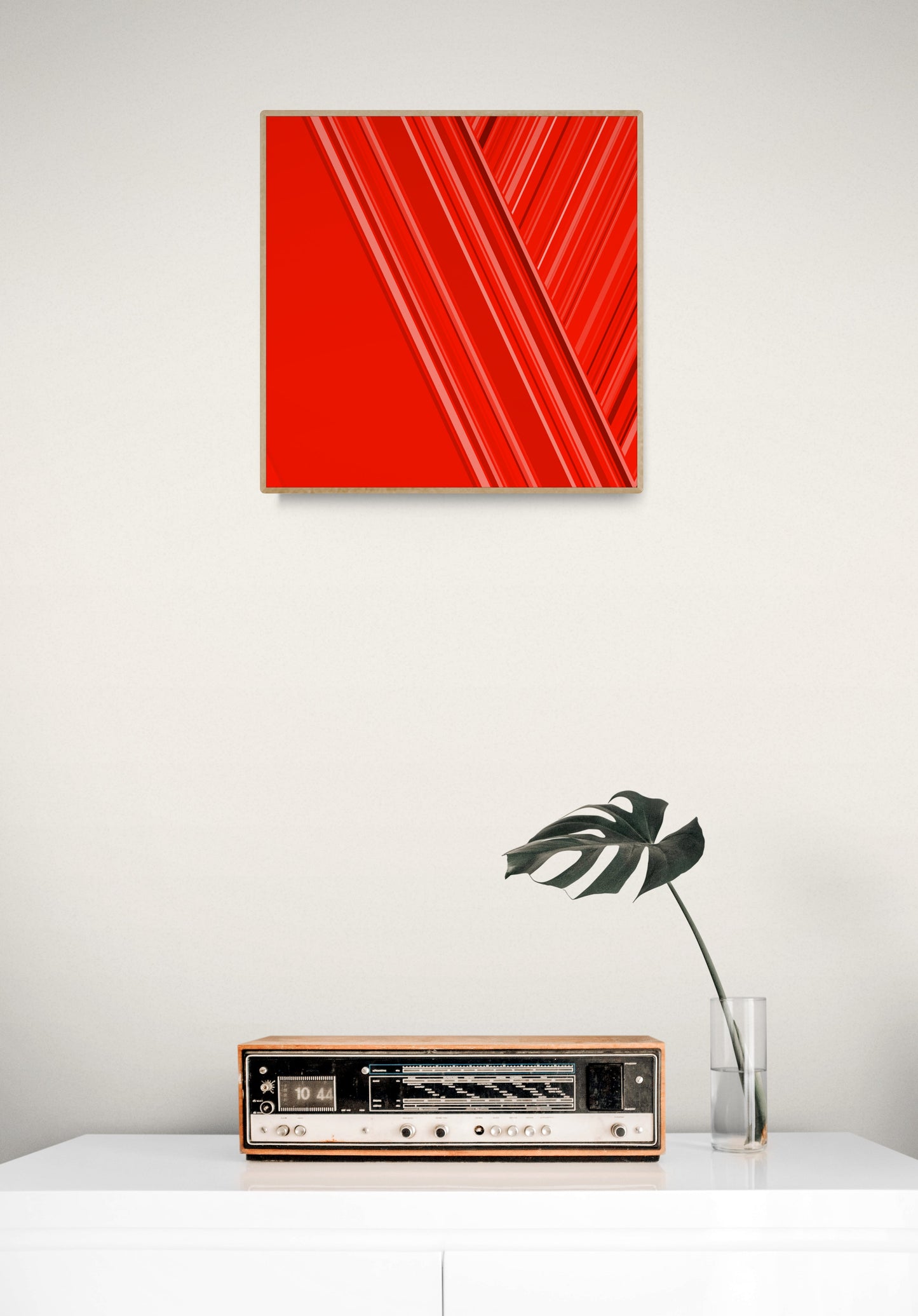 Red abstract print on a white wall above a vintage radio.
