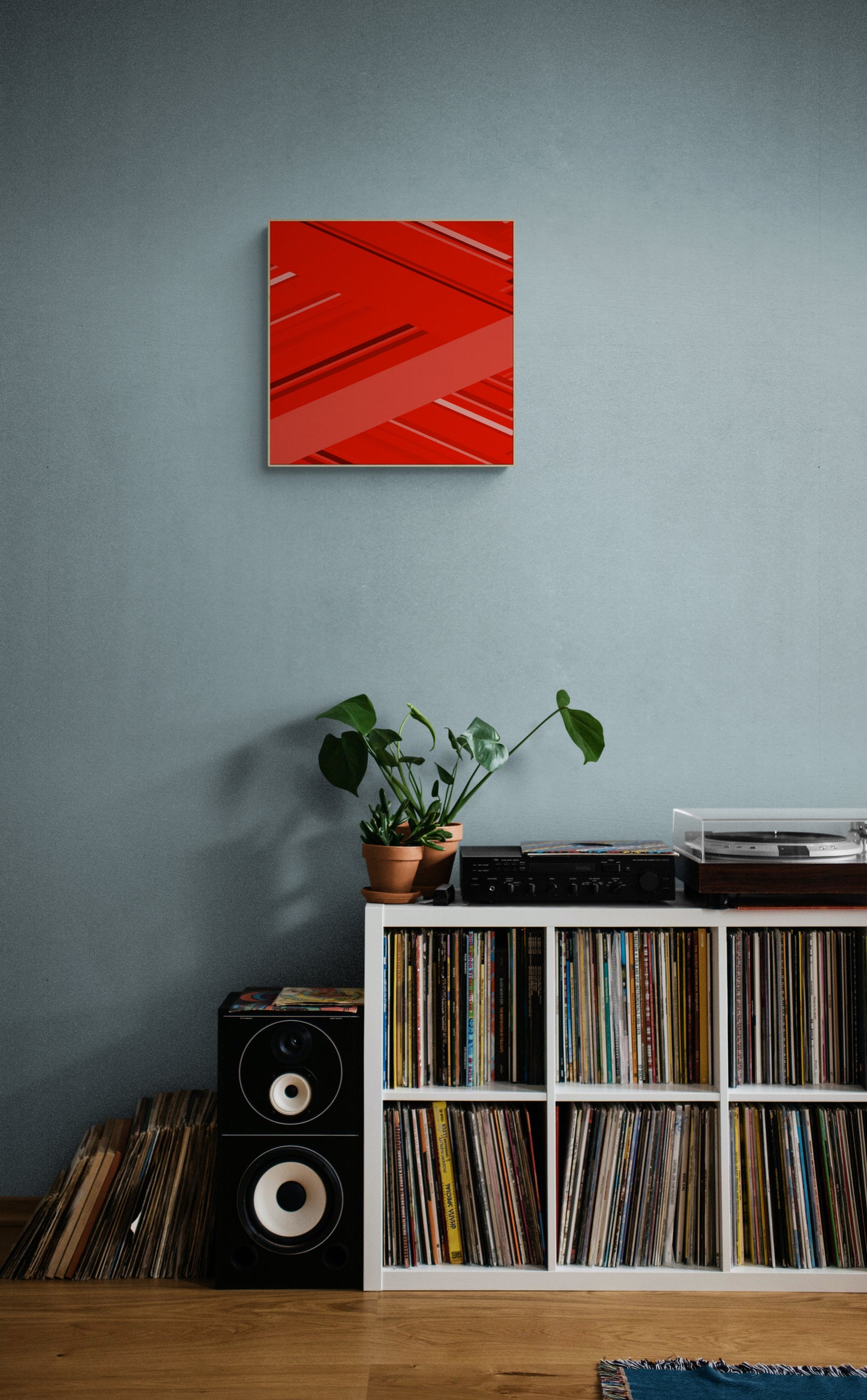 Red abstract print on a gray wall above a record player and speakers.