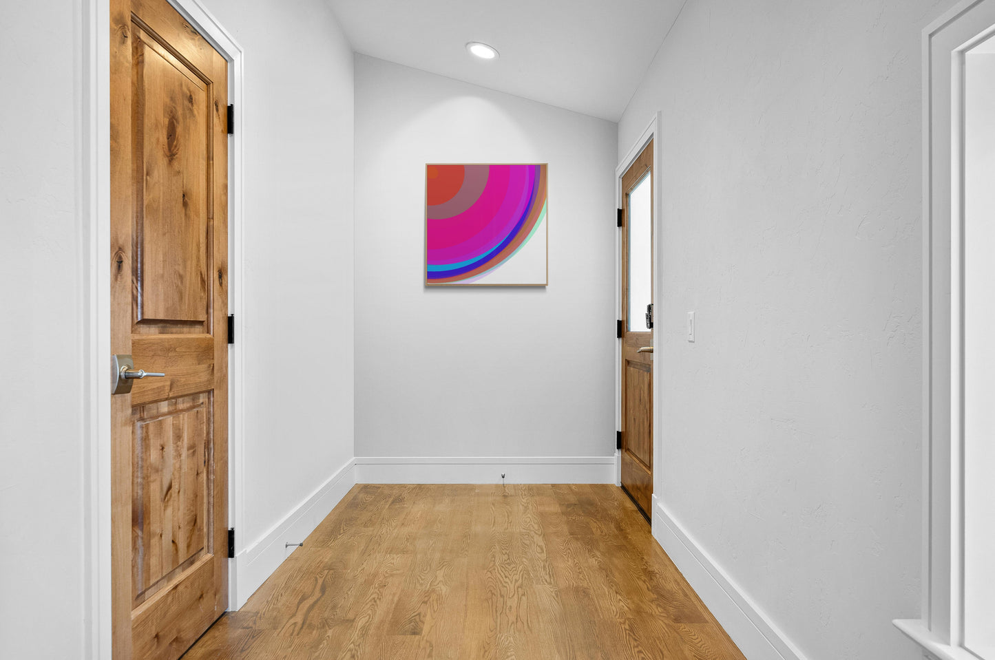 Foyer with wooden doors and an art print of colorful circular spheres with a gradient effect on the wall.