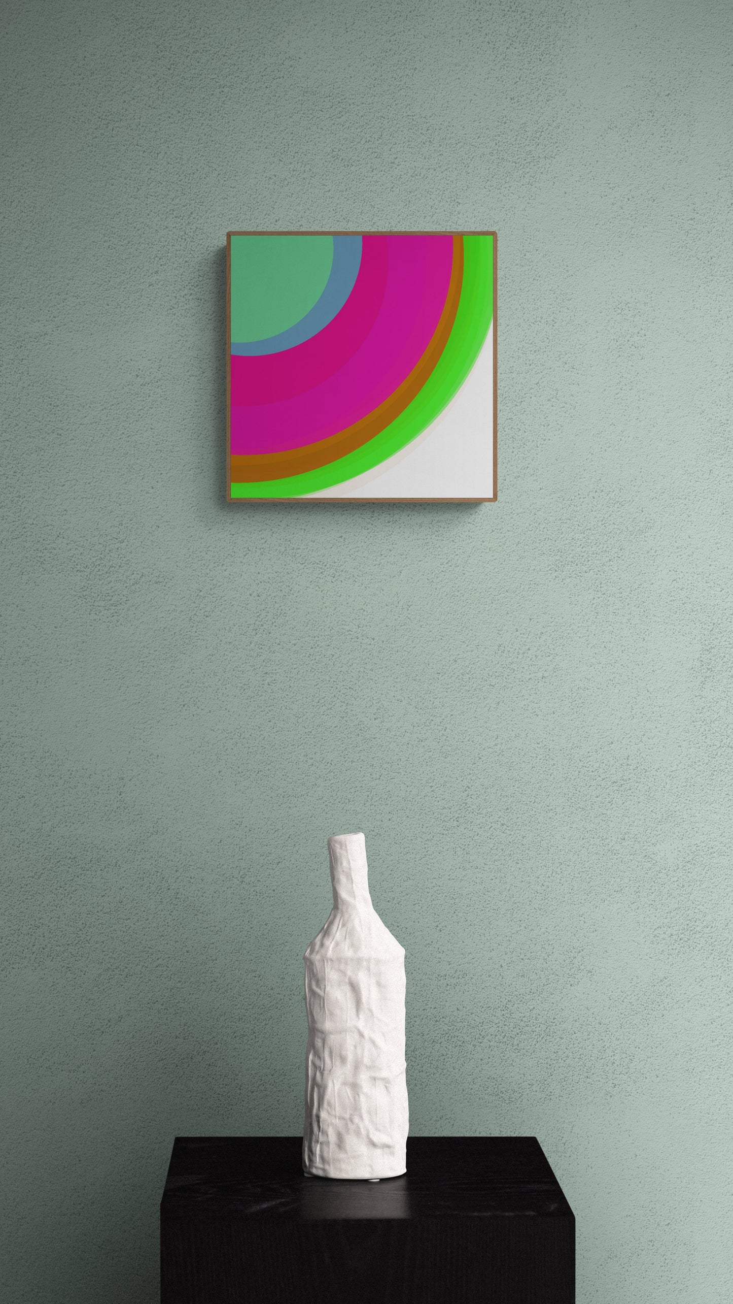 Art print of colorful circular sphere objects on a white background on a green wall with a white textured vase on a black surface.