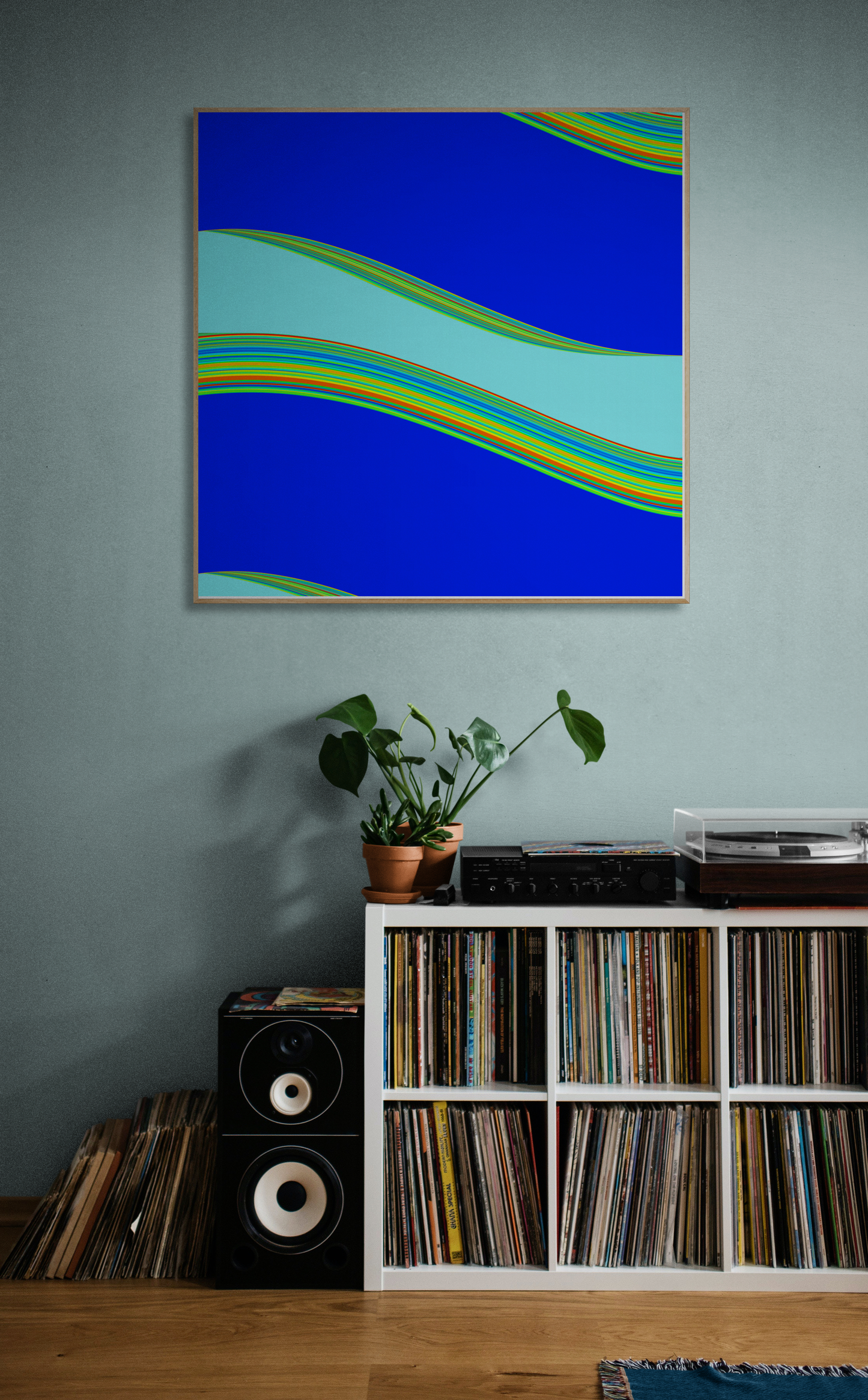 Abstract generative art print with blue and green colors on a wall above a record player and speakers.