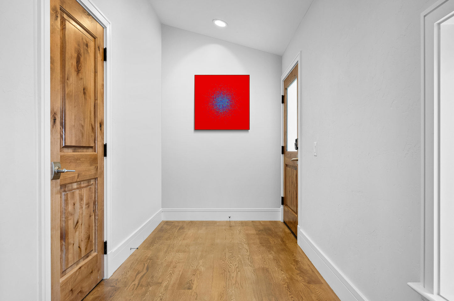 Foyer with wooden doors and a blue, green, purple confetti like patterned abstract print on a red background on the wall.