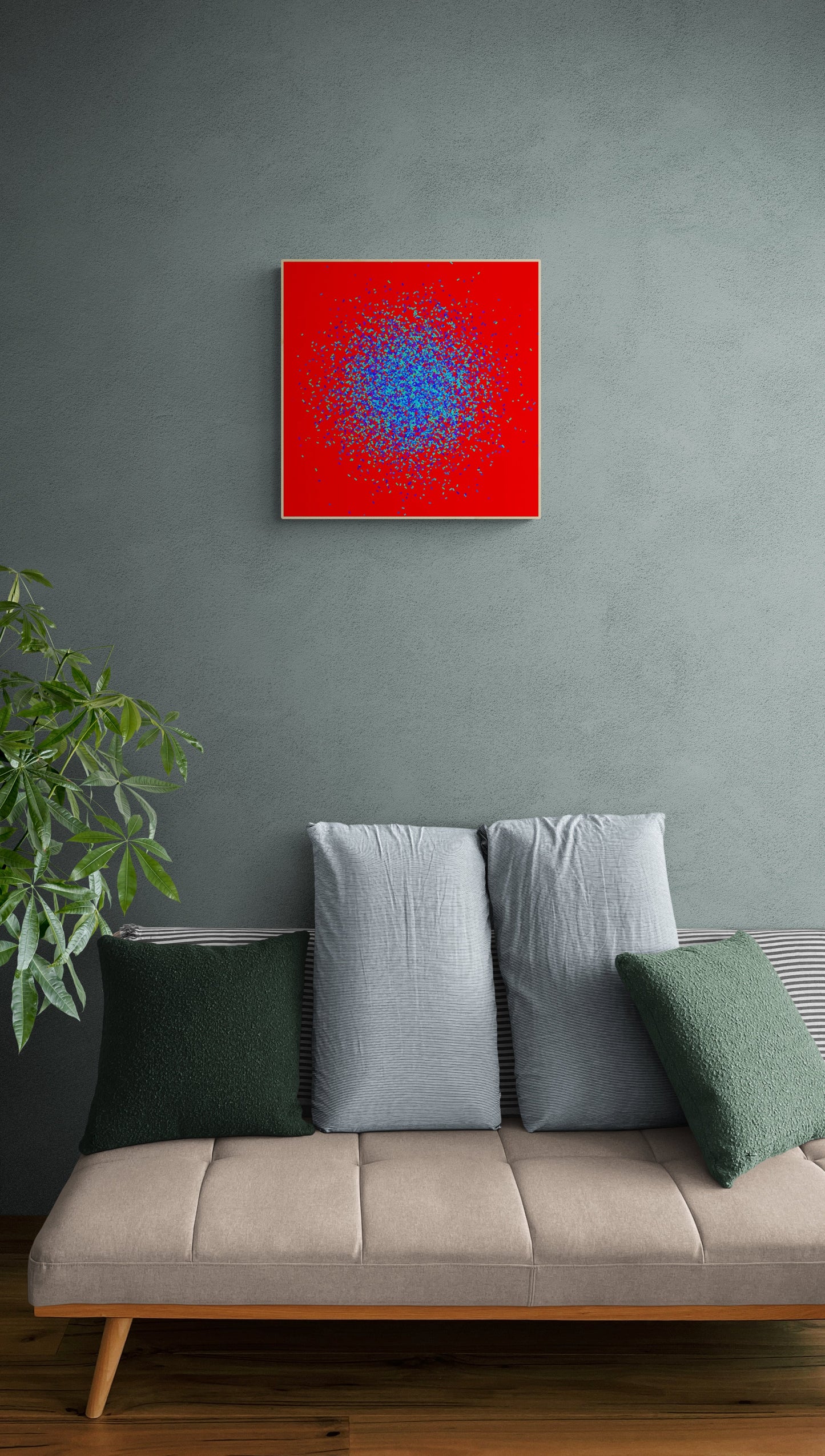 Framed abstract patterned art print of blue and green fragments on a red background on a gray wall above a beige sofa with green and gray cushions.