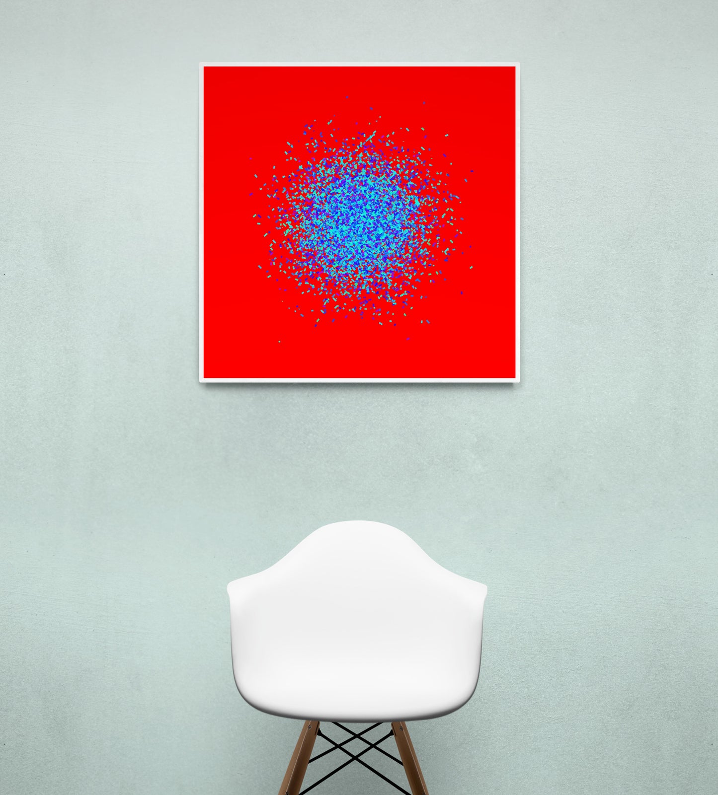 Abstract circle patterned art print of blue and green fragments on a red background, displayed on a light gray wall with a white chair below.