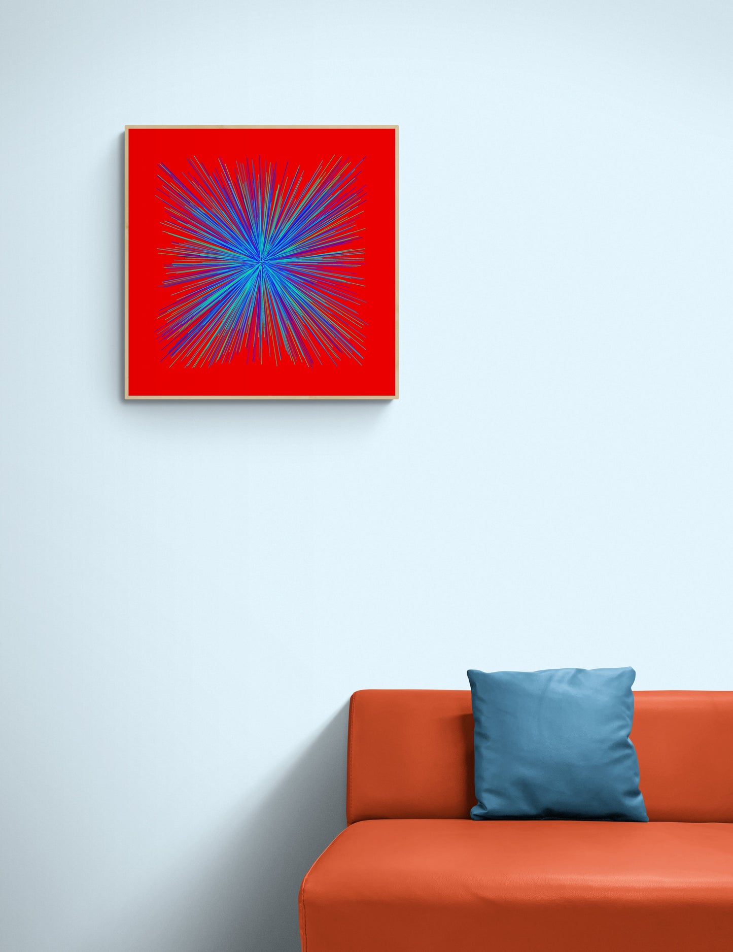 Abstract art print of colorful blue, green radialburst pattern on a red background on a wall above an orange sofa with a blue pillow.