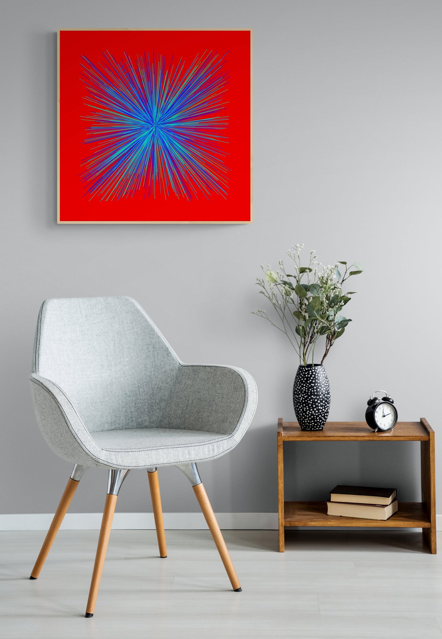 Modern interior with a gray chair, wooden side table, and abstract art print of colorful blue, green radialburst pattern on a red background