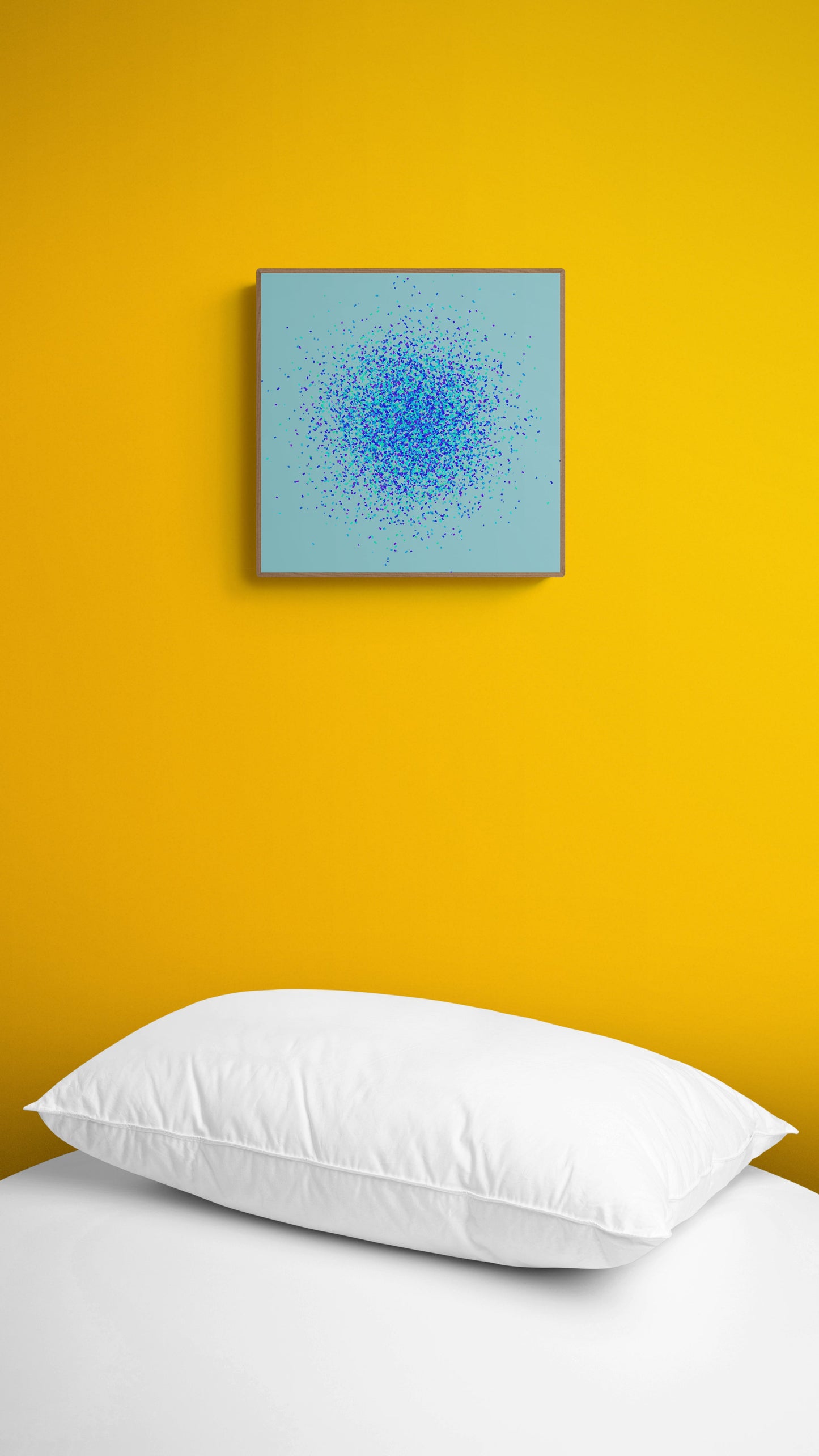 Abstract art print of blue, green and purple confetti like circular pattern on a light blue background on a yellow wall above a white bed