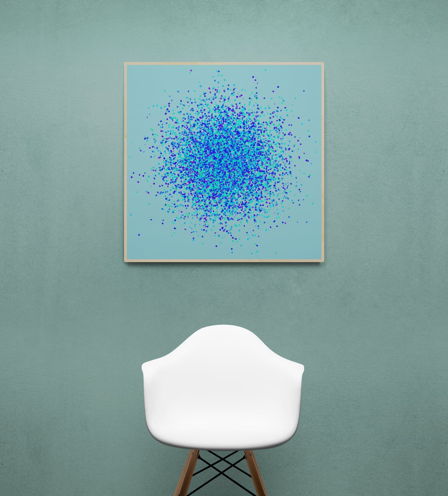 Abstract art print of blue, green and purple confetti like circular pattern on a light blue background, displayed on a green wall with a white chair.