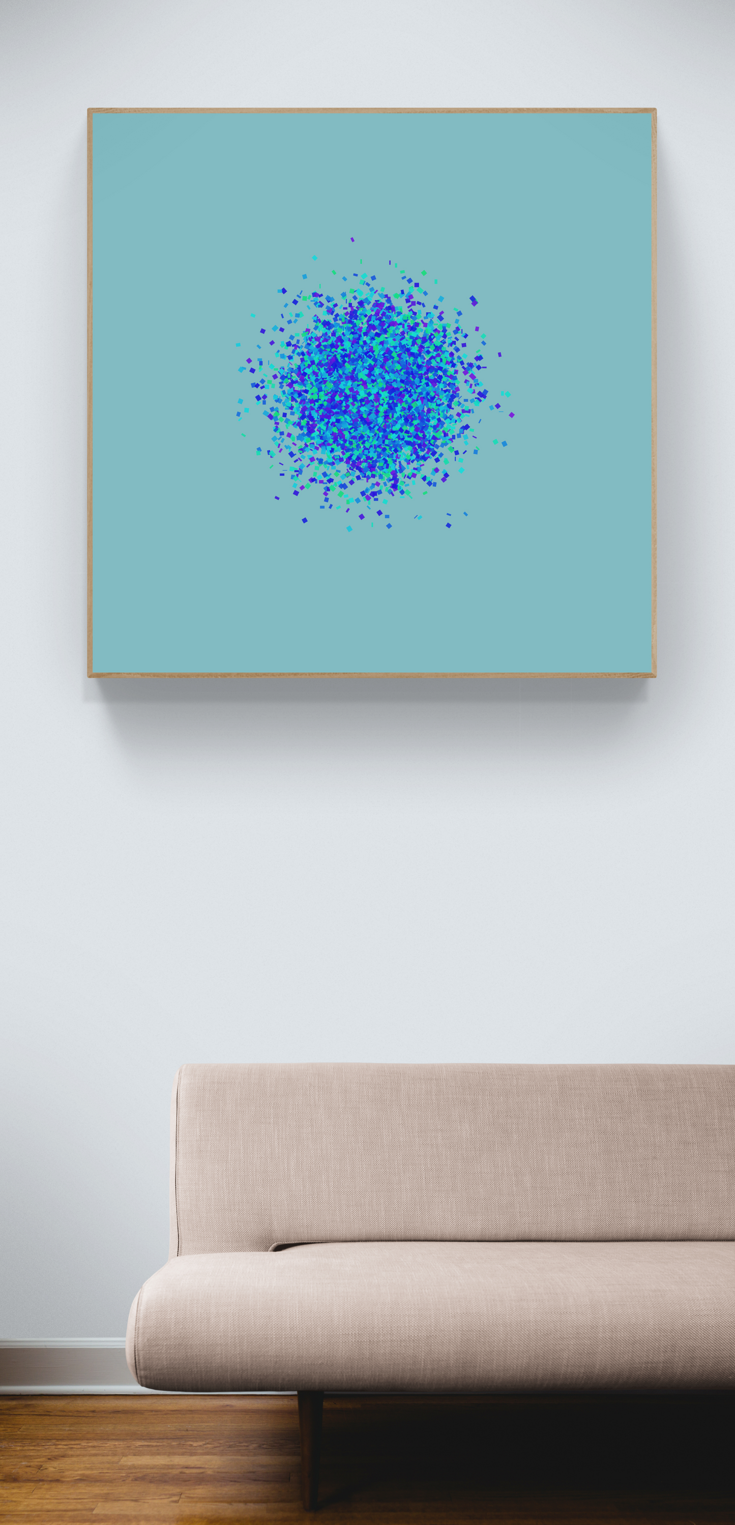 Framed abstract art print of blue, green and purple confetti like circular pattern on a light blue background, displayed above a beige sofa.