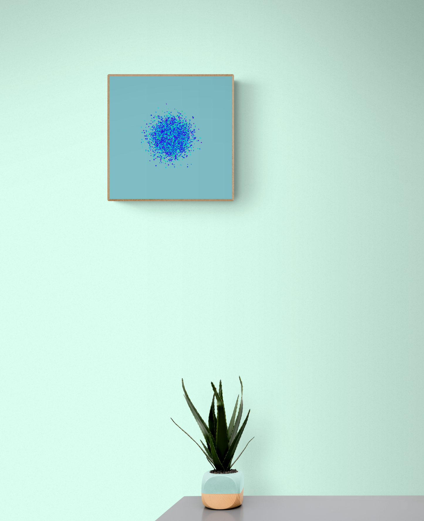 Abstract art print of blue, green and purple confetti like circular pattern on a light blue background on a light green wall, accompanied by a potted plant.