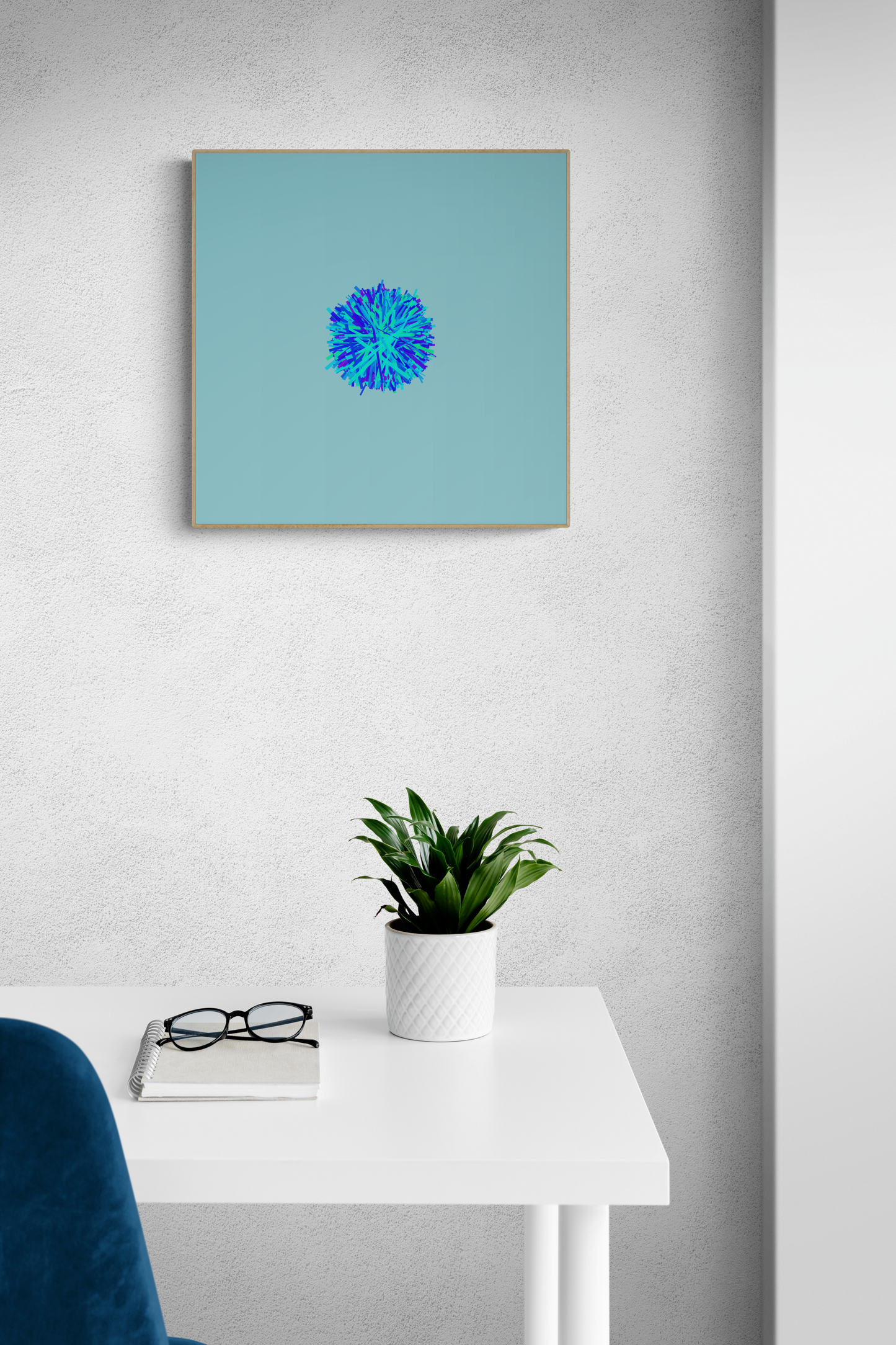 Abstract art print of blue, green and purple lines in a circular pattern on a light blue background on a white wall above a small table with a plant and glasses.