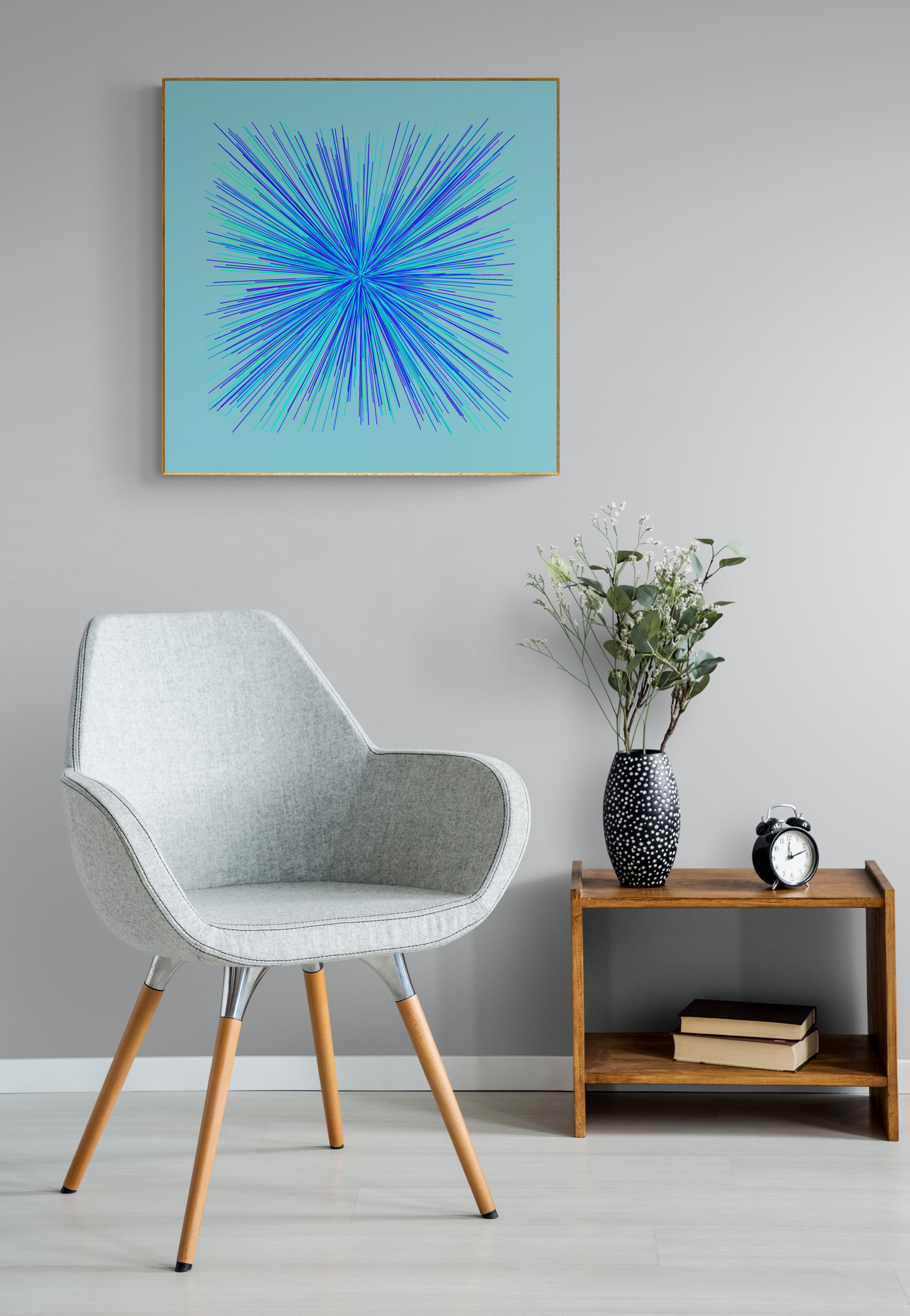 Modern interior with a gray chair, wooden side table, and abstract art print of blue, green and purple lines in a radial burst pattern on a light blue background on a gray wall.