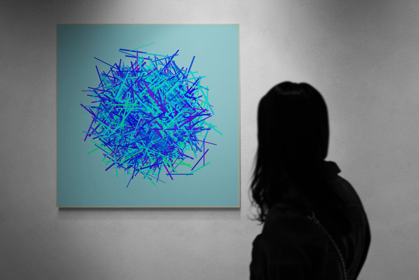 Person viewing an abstract art print of blue, green and purple lines in a circular pattern on a light blue background on a gray wall