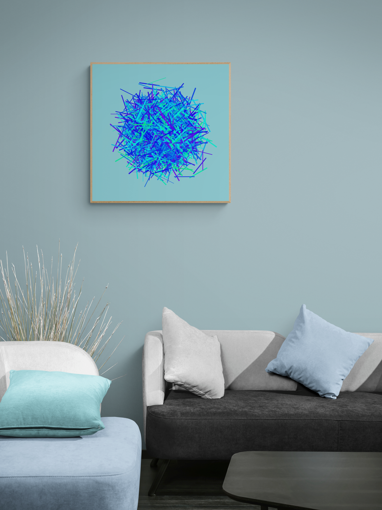 Abstract art print of blue, green and purple lines in a circular pattern on a light blue background on a light blue wall above a sofa with decorative pillows.