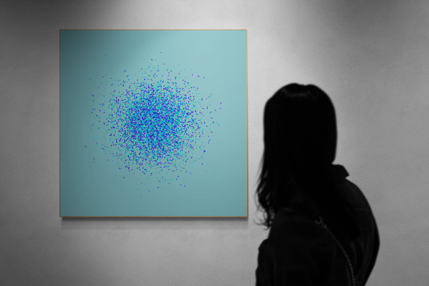 Person observing a modern abstract art print of blue, green and purple confetti like circular pattern on a light blue background on a teal background.