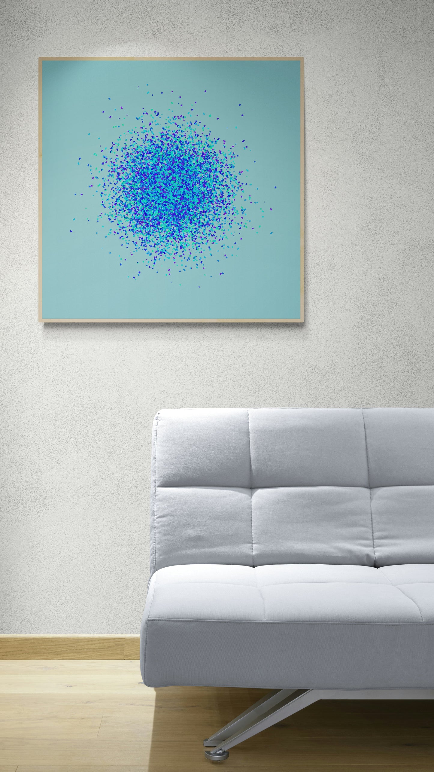 Framed abstract art print of blue, green and purple confetti like circular pattern on a light blue background on a light blue background, displayed above a gray sofa.