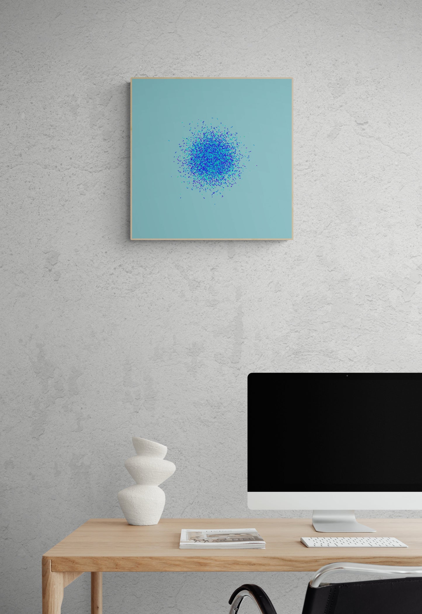 Modern office setup with an abstract art print of blue, green and purple confetti like circular pattern on a light blue background on a gray wall.