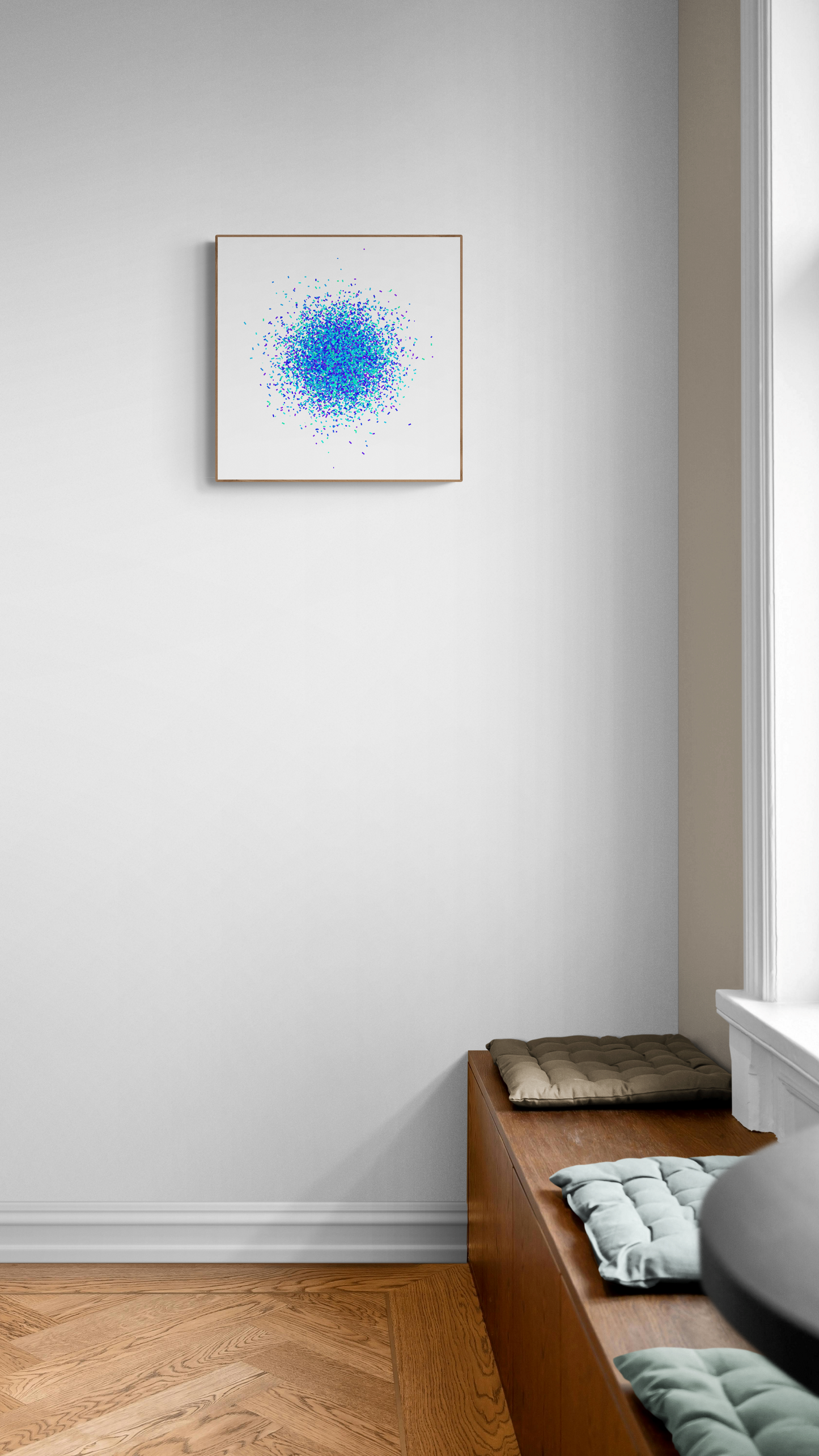 Blue and green speckle patterned abstract art print on a white background on a white wall above a wooden bench.