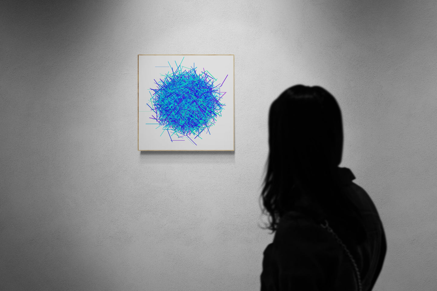 Person viewing an abstract patterned print of intersecting blue, green and purple lines on a white background on a gray wall