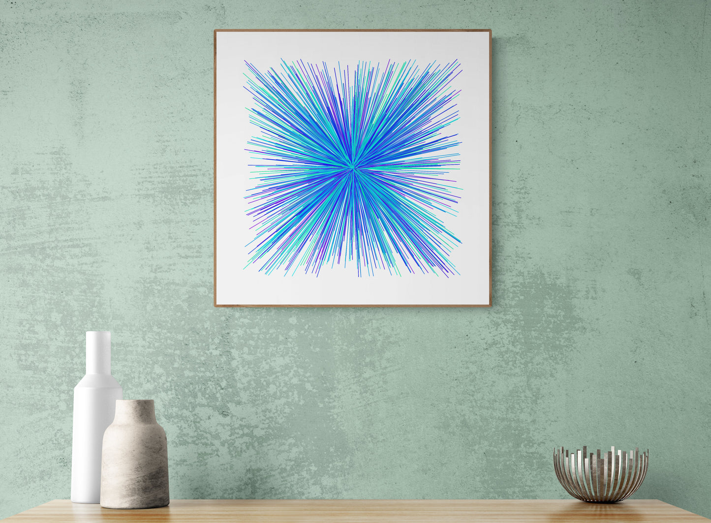 Framed abstract art print with blue and green starburst pattern on a green wall.