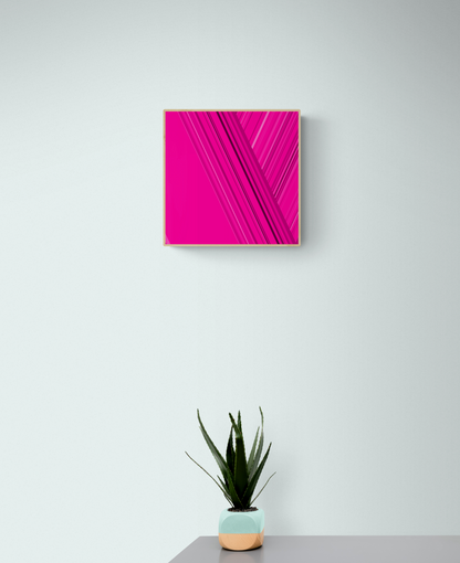 Art print  of abstract design with intersecting lines on a pink backgroundon a white wall with a potted plant below.