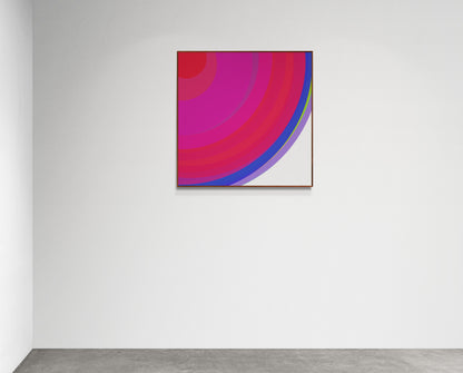 Art print of colorful concentric circles with red, pink, and blue on a white background on a white wall
