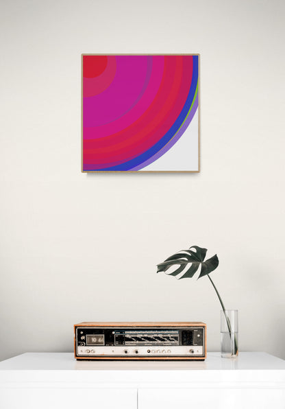 Art print of colorful concentric circles with red, pink, and blue on a white background on a white wall above a vintage radio.
