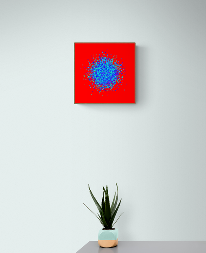 Blue, green, purple confetti like patterned abstract print on a red background, placed above a potted plant on a gray surface.