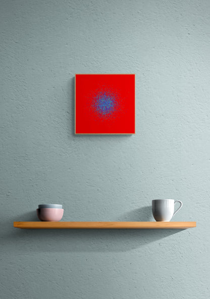 Blue, green, purple confetti like patterned abstract print on a red background on a gray wall above a wooden shelf with two cups.