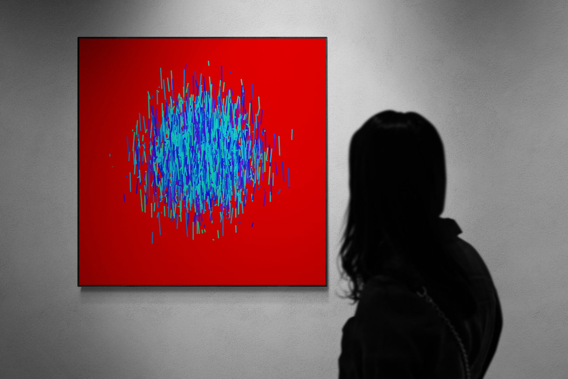 Person viewing an abstract patterned art print of blue and green lines on a red background