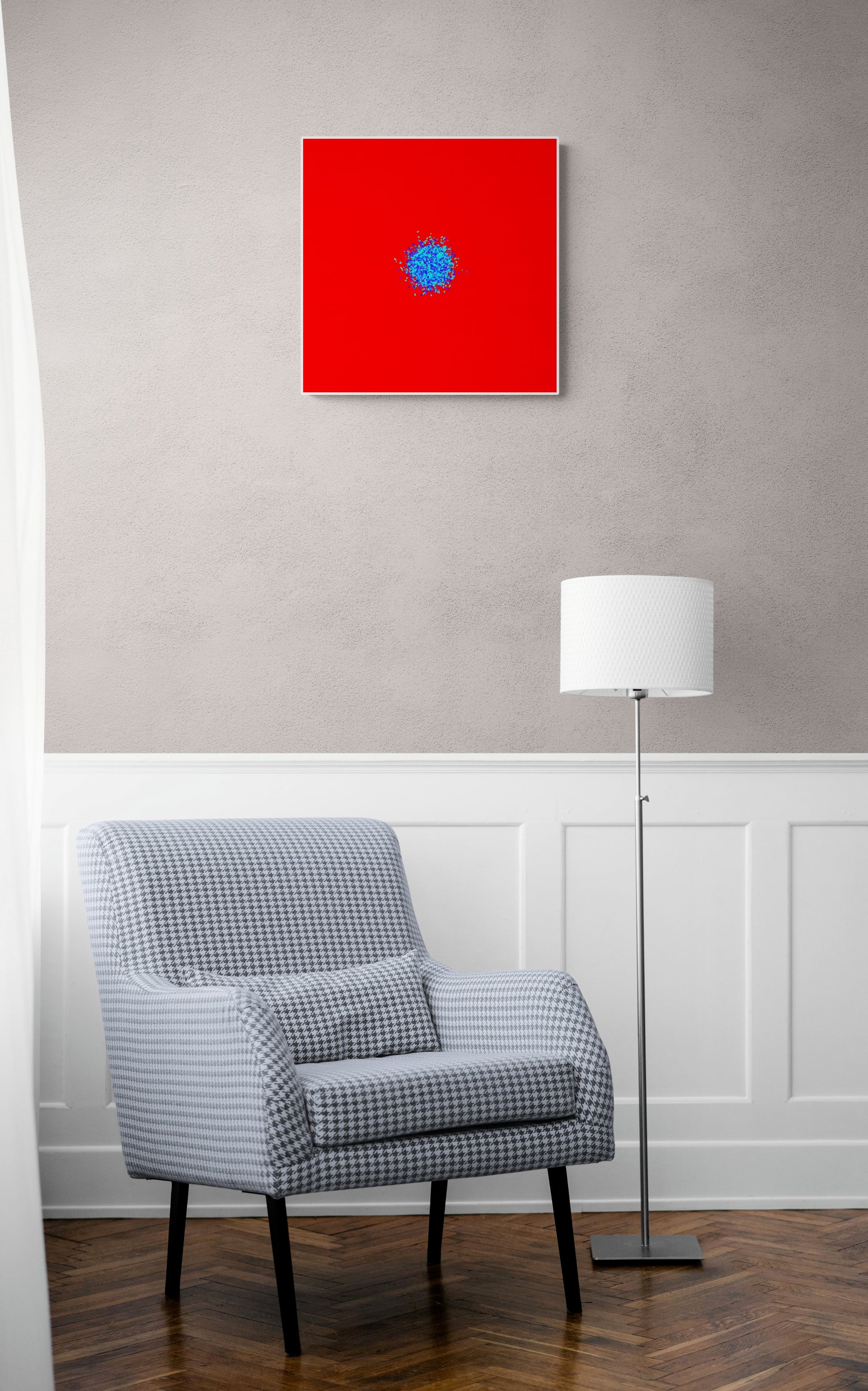 Gray checkered armchair in a room with an abstract patterned art print of ball of blue and green fragments on a red background on the wall.