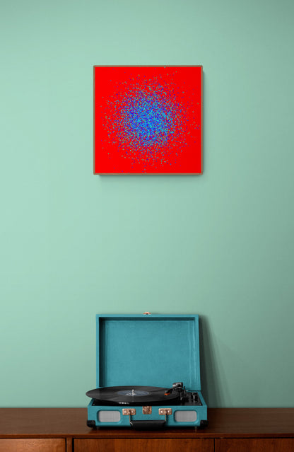 Teal record player on a wooden surface with an abstract patterned art print of blue and green fragments on a red background on the wall.
