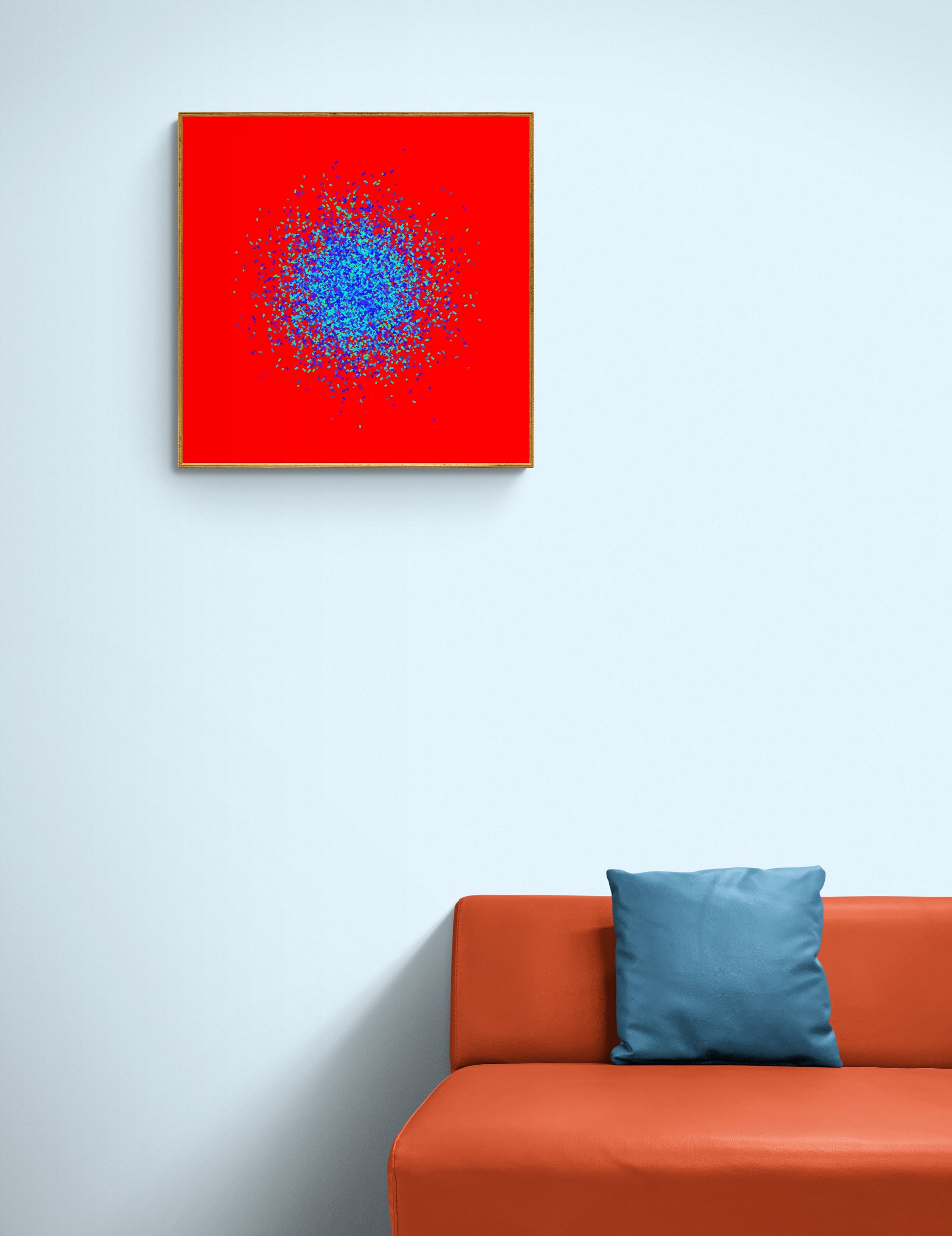 Blue, green, purple confetti like patterned abstract print on a red background on a light gray wall above an orange sofa with a blue pillow.
