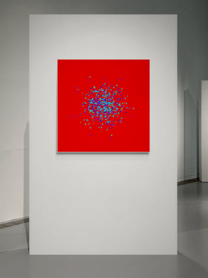 Blue, green, purple confetti like patterned abstract print on a red background in an art gallery.