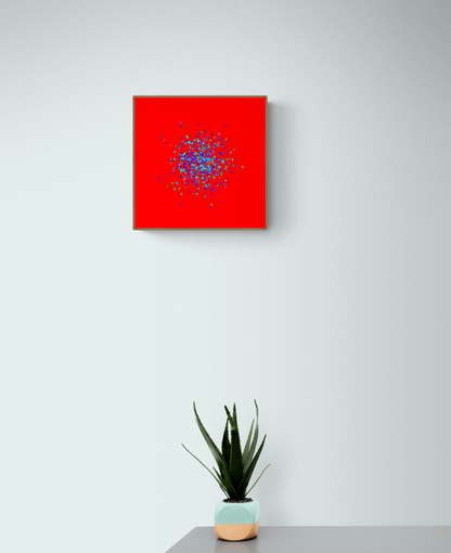 Blue, green, purple confetti like patterned abstract print on a red background on a light gray wall, with a potted plant below.