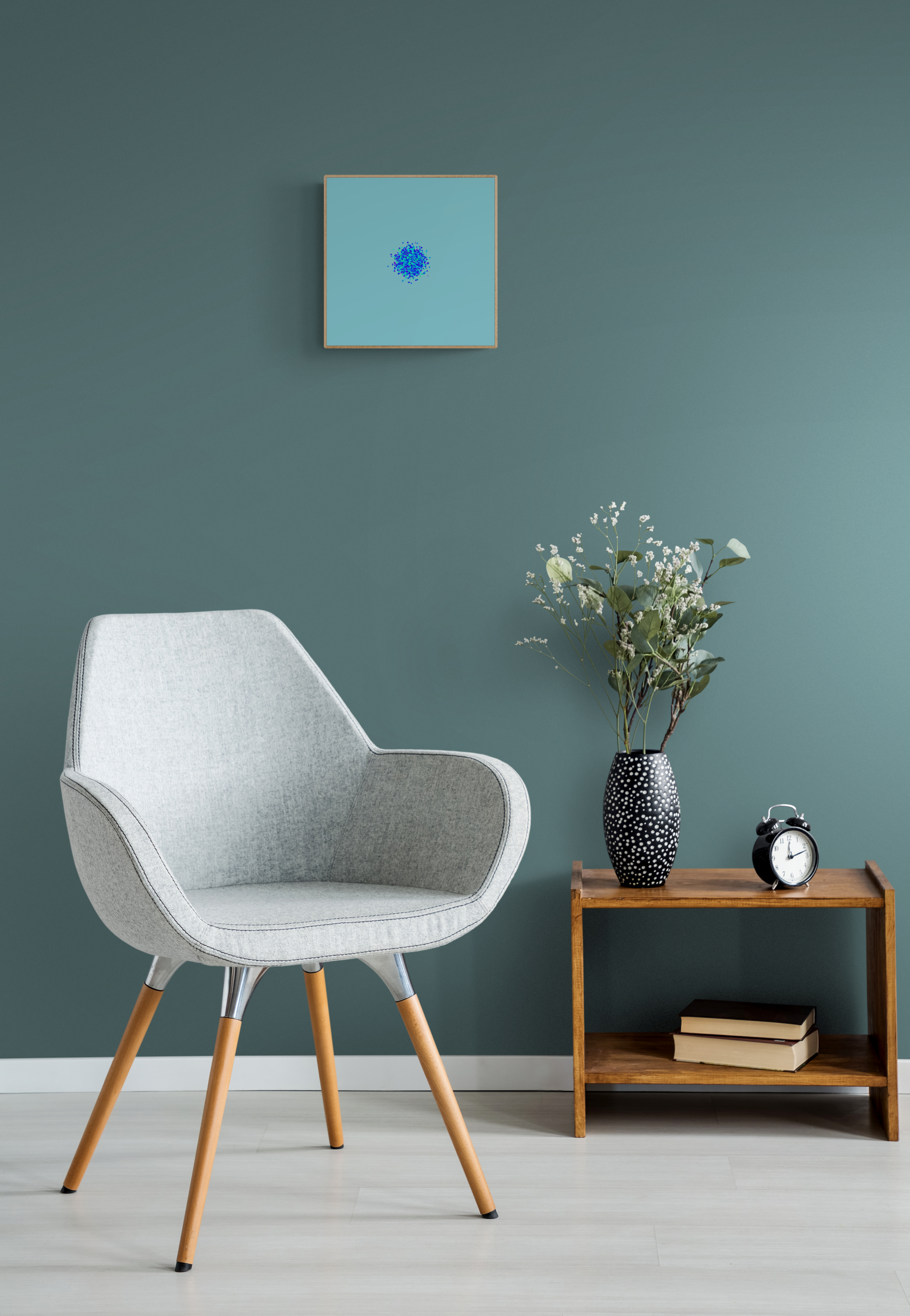 Modern chair in a room with a teal wall, small table with decor items, and abstract art print of blue, green and purple confetti like circular pattern on a light blue background