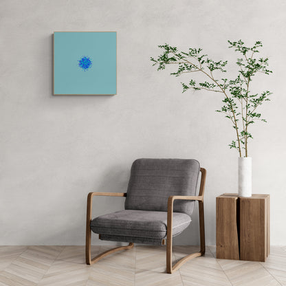 Gray armchair in a room with an abstract art print of blue, green and purple confetti like circular pattern on a light blue background on the wall and a plant in a white vase.