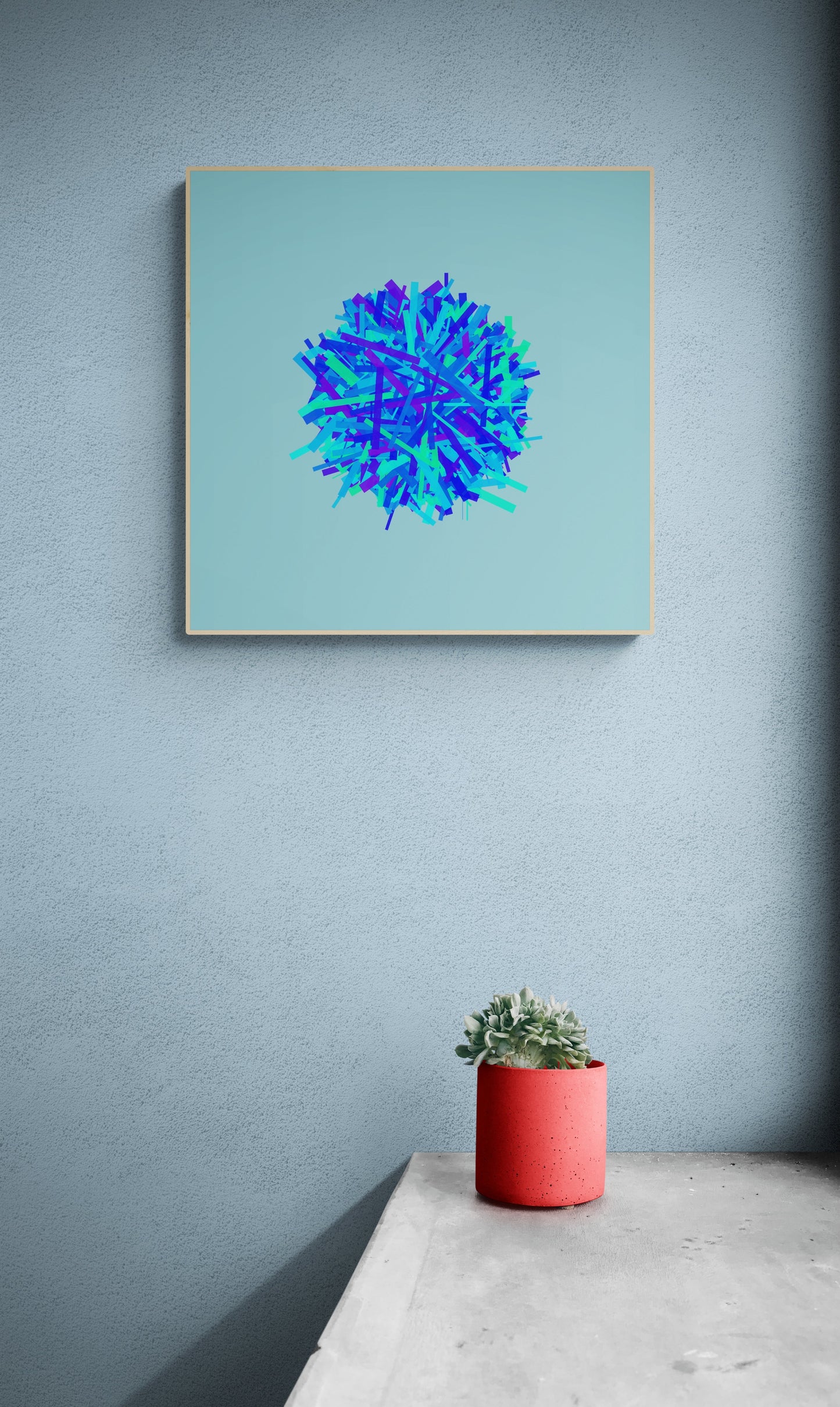 Framed abstract art print of blue, green and purple lines in a circular pattern on a light blue background on a light gray wall, accompanied by a red pot with a plant.