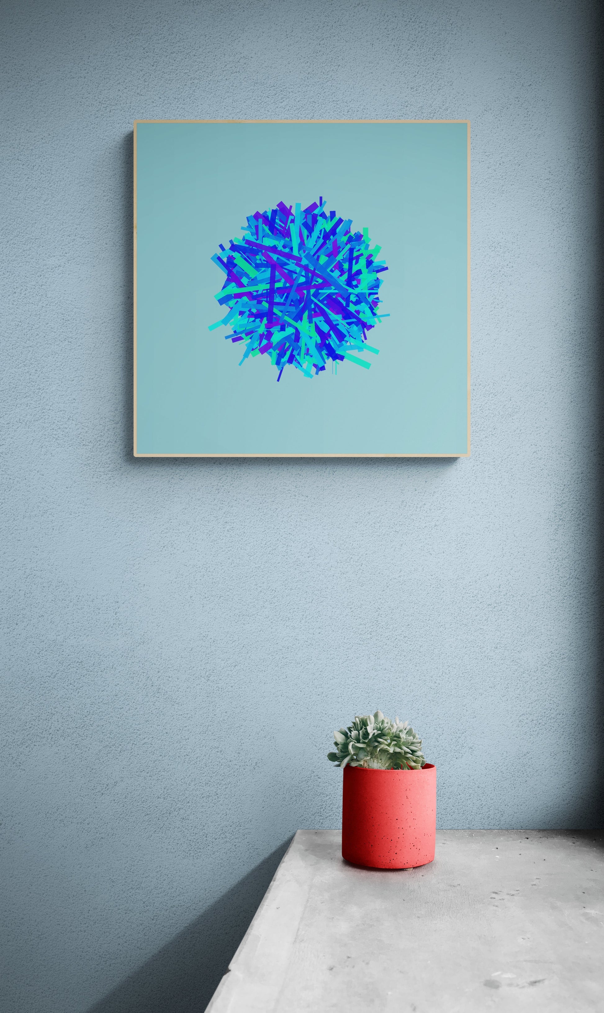 Framed abstract art print of blue, green and purple lines in a circular pattern on a light blue background on a light gray wall, accompanied by a red pot with a plant.