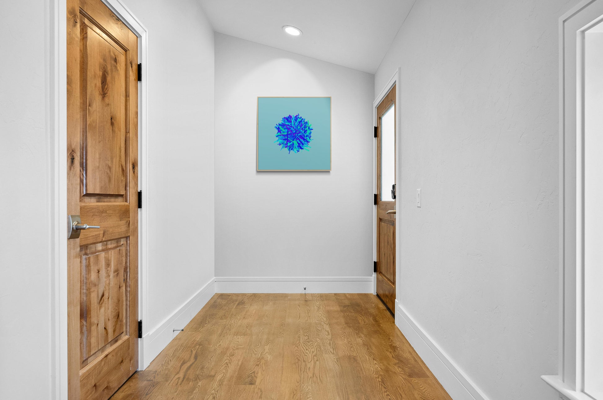 Foyer with wooden doors and an abstract art print of blue, green and purple lines in a circular pattern on a light blue background on the wall.