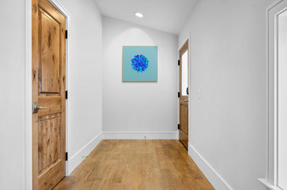 Foyer with wooden doors and an abstract art print of blue, green and purple lines in a circular pattern on a light blue background on the wall.