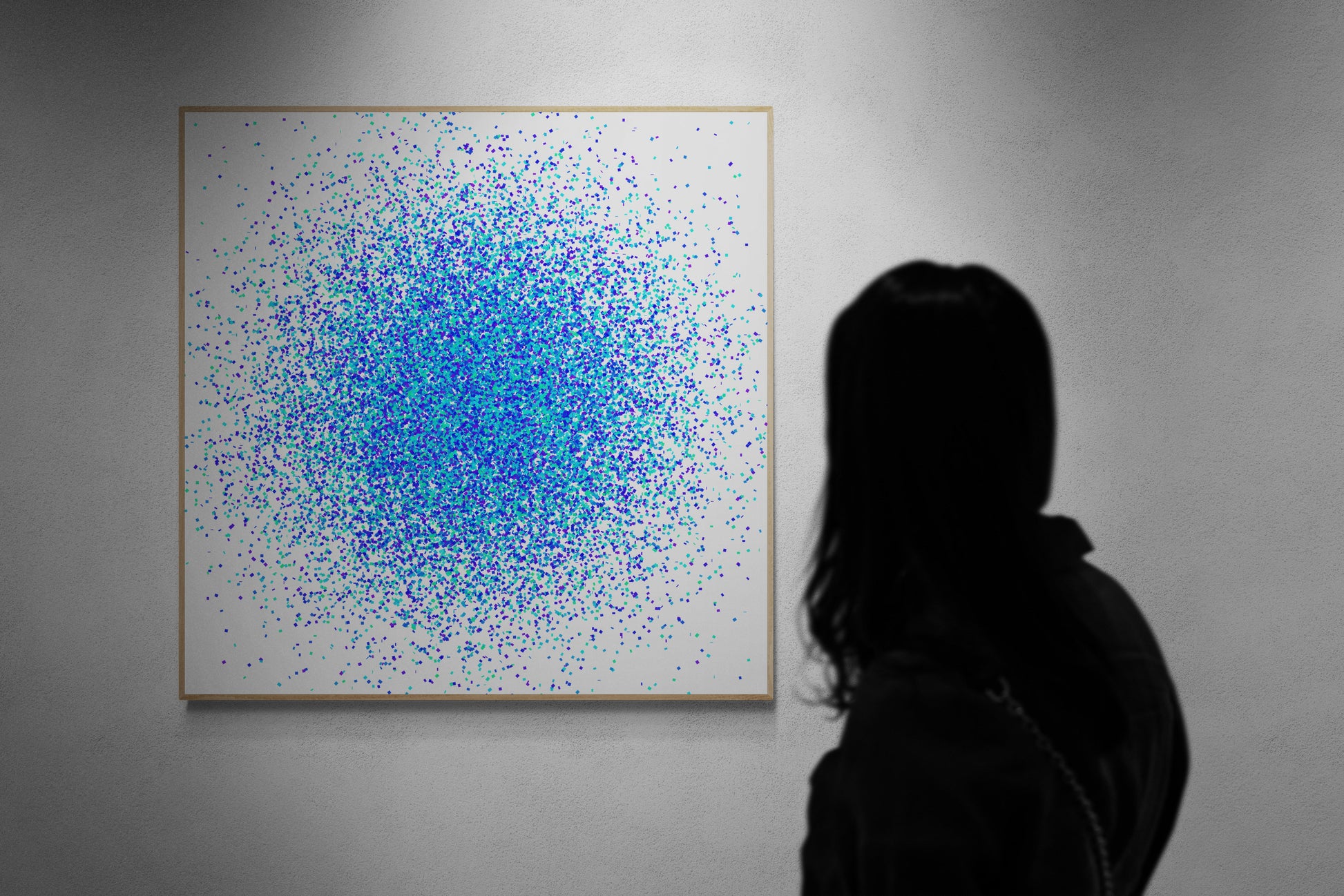 Person viewing a large abstract print with blue, green and white dots on a gray wall