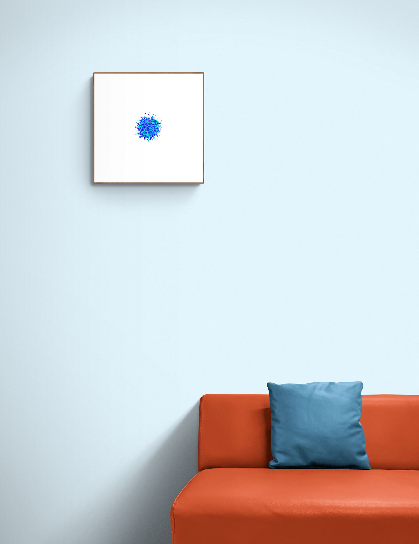 Blue and green colour particle like circle abstract art print on a white background on a light blue wall above an orange sofa with a blue pillow.